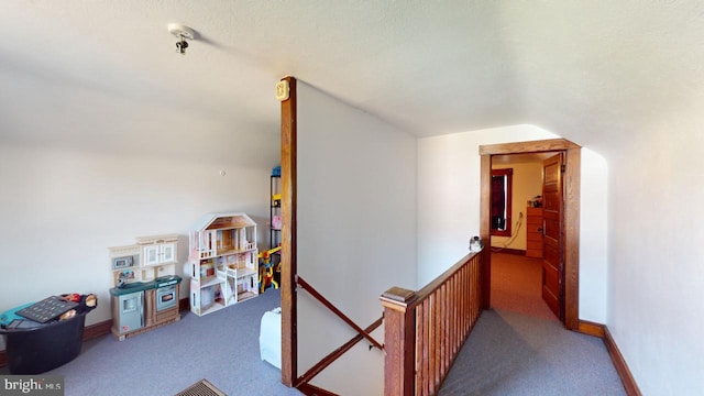 corridor with vaulted ceiling, carpet, and a textured ceiling