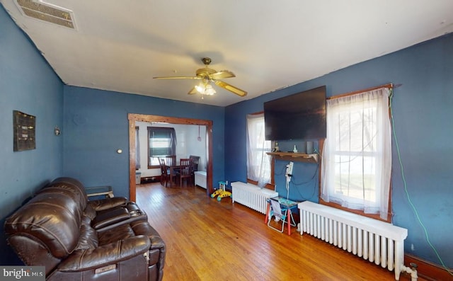 living room featuring ceiling fan, wood-type flooring, and radiator heating unit