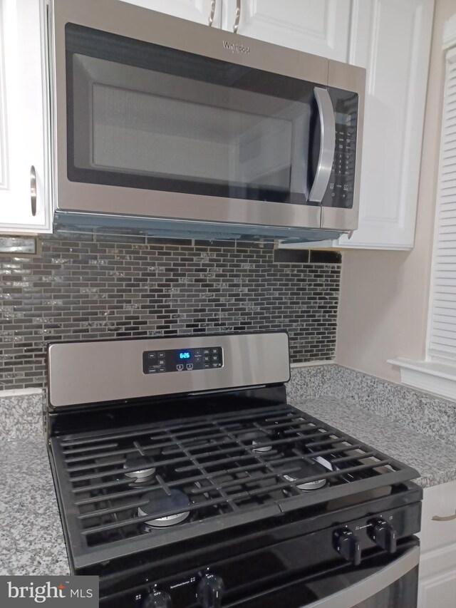 interior details featuring white cabinets, stainless steel appliances, and backsplash