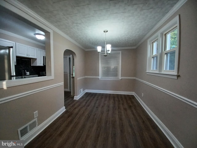 unfurnished dining area featuring an inviting chandelier, crown molding, sink, and dark wood-type flooring