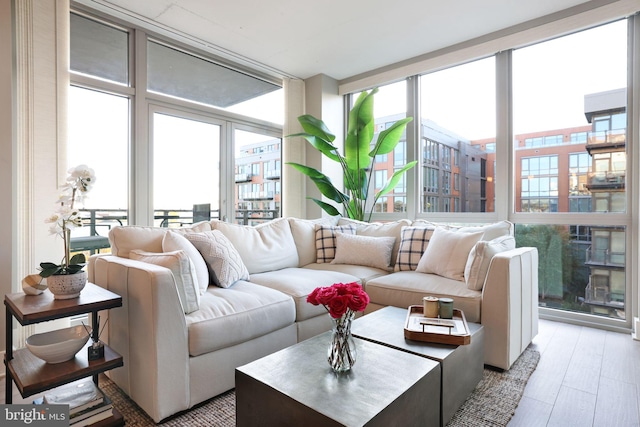 living room with light wood-type flooring, a wall of windows, and plenty of natural light