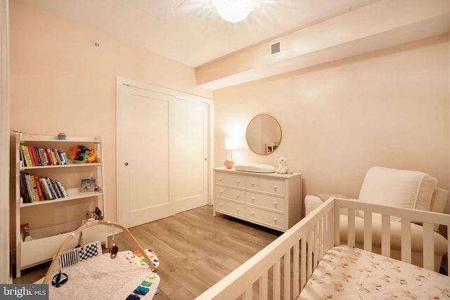 bedroom with hardwood / wood-style floors, a nursery area, and a closet