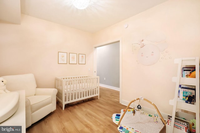 bedroom with a nursery area and light hardwood / wood-style flooring