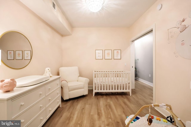 bedroom featuring a crib and light hardwood / wood-style floors