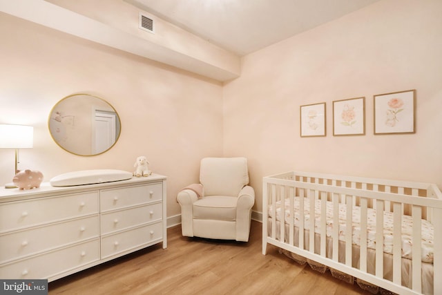 bedroom featuring a crib and light hardwood / wood-style flooring