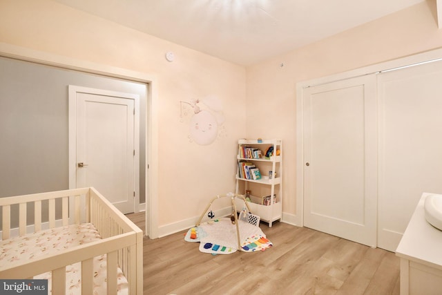 bedroom with a crib and light wood-type flooring