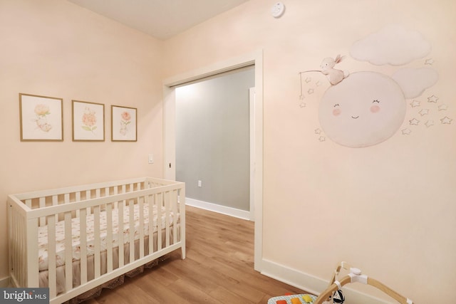 bedroom with a crib and hardwood / wood-style floors