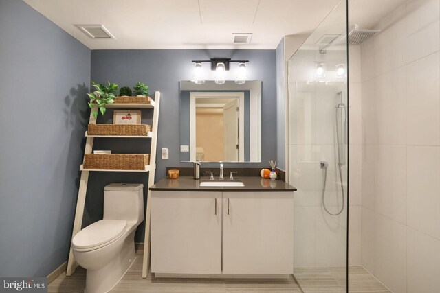 bathroom with hardwood / wood-style floors, vanity, toilet, and a shower