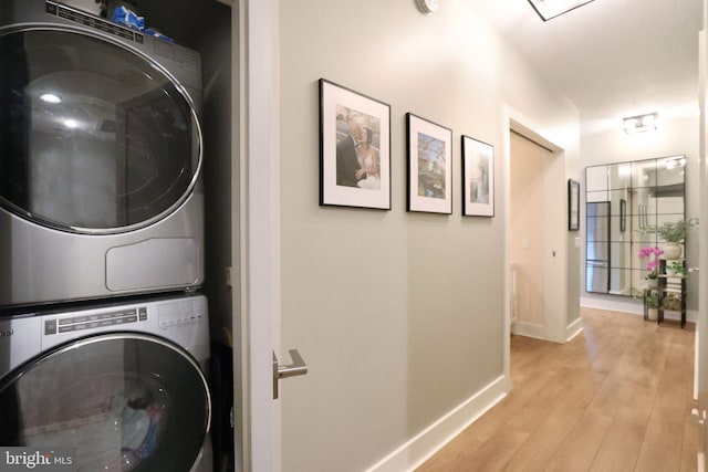 laundry area with stacked washer / dryer and light hardwood / wood-style flooring