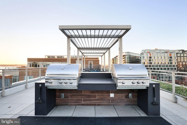 patio terrace at dusk featuring a balcony and grilling area