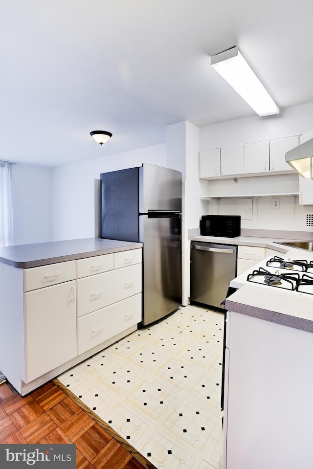 kitchen with light parquet flooring, white cabinetry, and stainless steel appliances