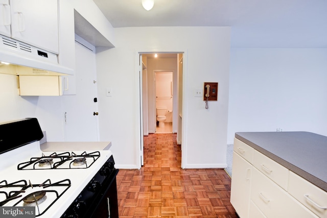 kitchen featuring white gas range, light parquet floors, extractor fan, and white cabinetry