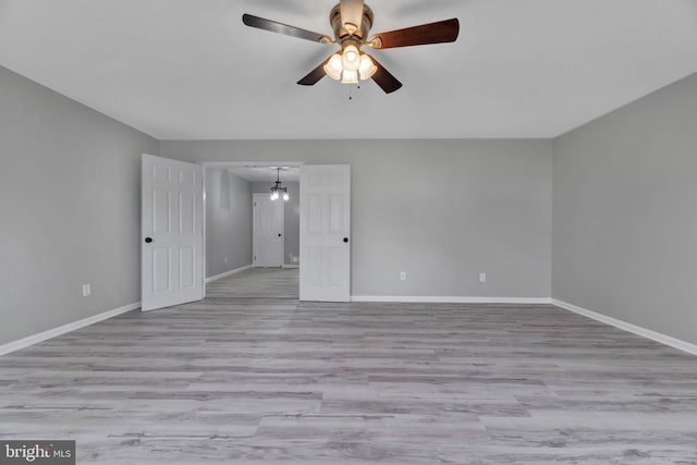 empty room with ceiling fan with notable chandelier and light wood-type flooring