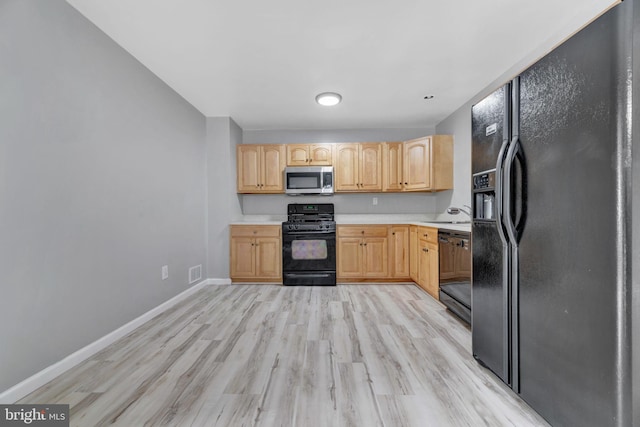 kitchen featuring black appliances, light hardwood / wood-style floors, sink, and light brown cabinetry