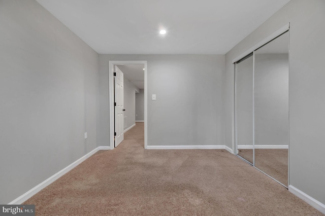 unfurnished bedroom featuring light carpet and a closet