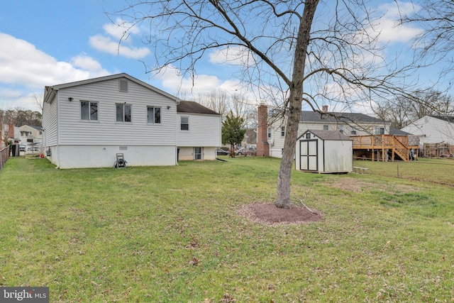 rear view of house featuring a yard, a deck, and a storage shed