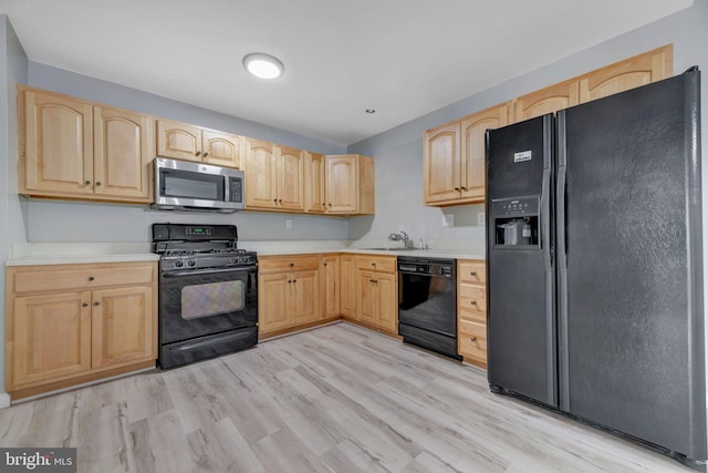 kitchen with black appliances, light hardwood / wood-style floors, sink, and light brown cabinets