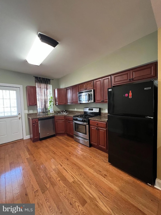 kitchen featuring light wood-type flooring, stainless steel appliances, and dark stone countertops