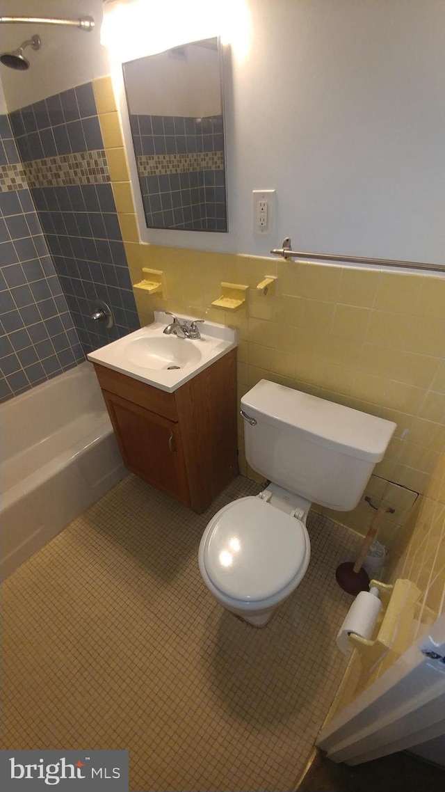 full bathroom with shower / tub combo, toilet, tile patterned floors, tile walls, and vanity