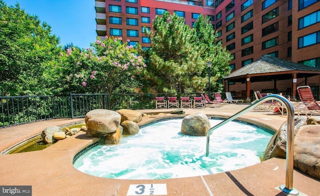 view of swimming pool featuring a gazebo, a hot tub, a swimming pool, and fence