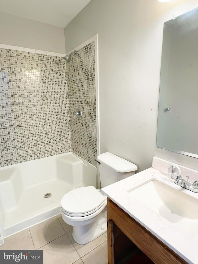 bathroom featuring vanity, toilet, tile patterned floors, and tiled shower