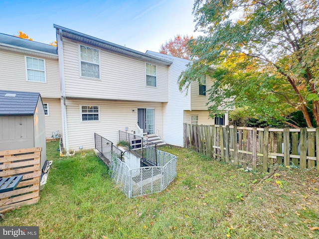 back of property with a storage shed and a lawn