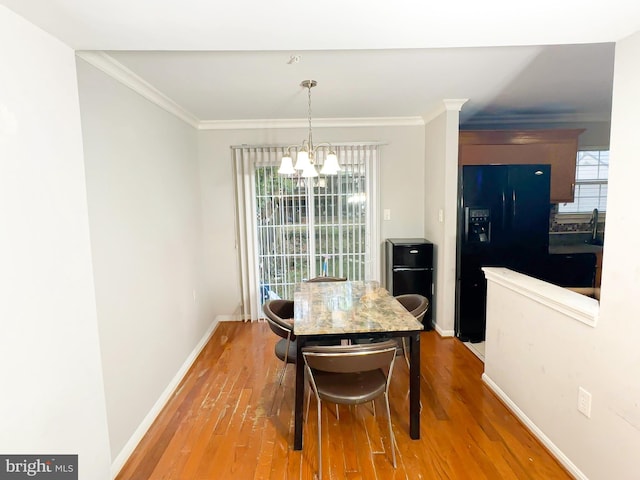 dining space featuring a notable chandelier, ornamental molding, and hardwood / wood-style flooring