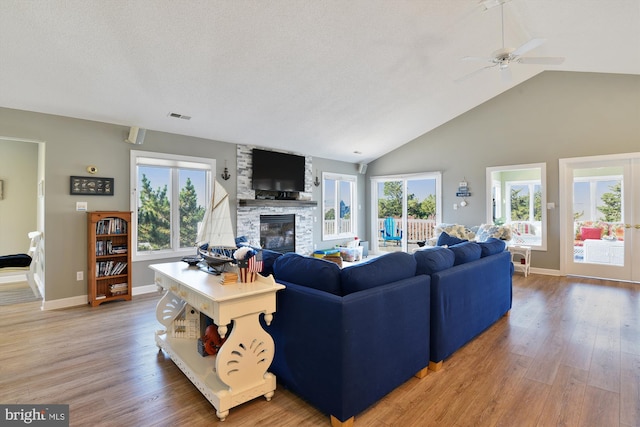 living room featuring a fireplace, wood-type flooring, a healthy amount of sunlight, and ceiling fan