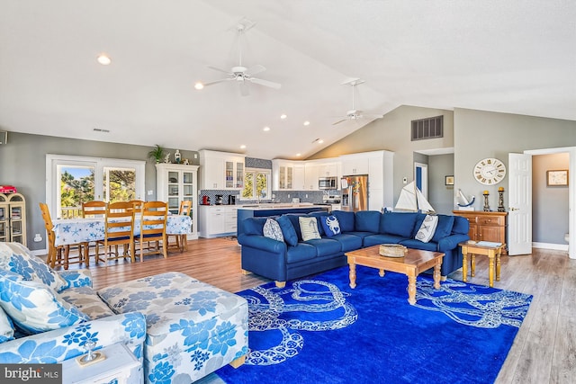 living room with light hardwood / wood-style floors, lofted ceiling, and ceiling fan