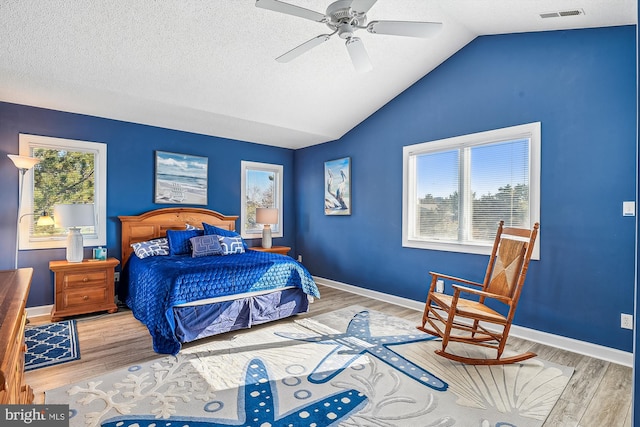 bedroom featuring hardwood / wood-style flooring, a textured ceiling, lofted ceiling, and ceiling fan