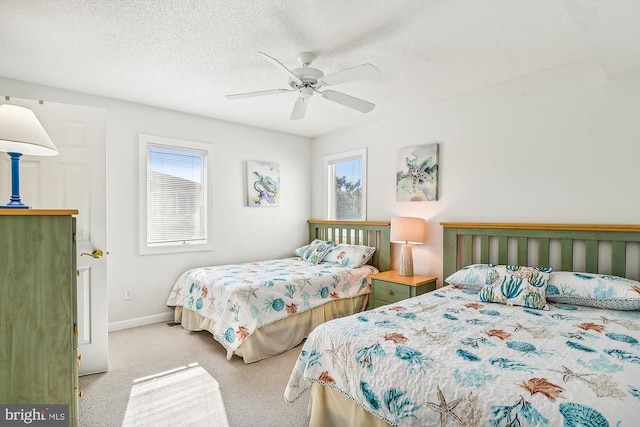 bedroom with a textured ceiling, light colored carpet, and ceiling fan