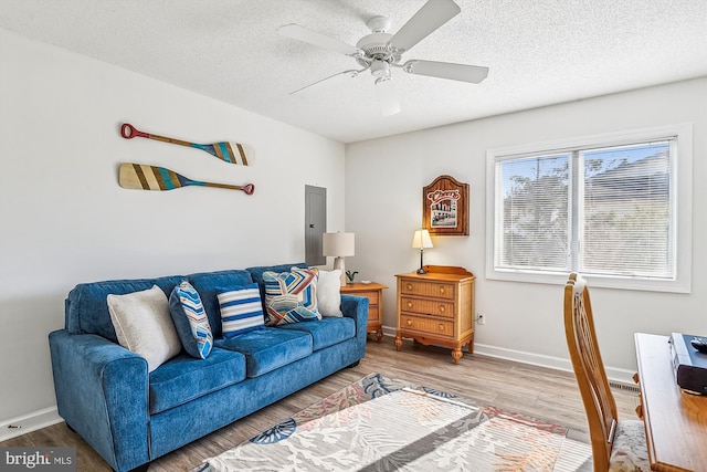 living room featuring a textured ceiling, electric panel, wood-type flooring, and ceiling fan