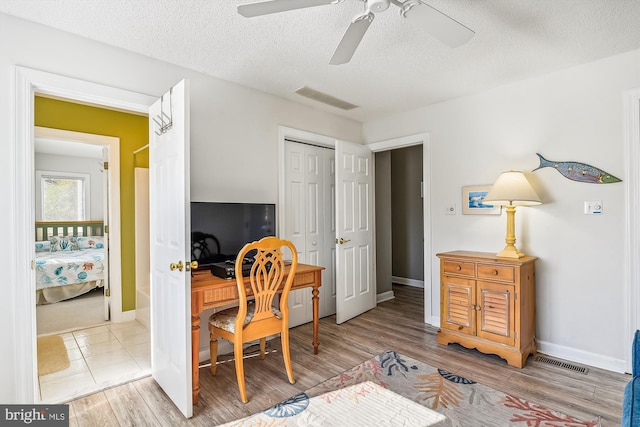 office area with ceiling fan, a textured ceiling, and light hardwood / wood-style flooring