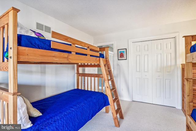 bedroom featuring light colored carpet, a textured ceiling, and a closet