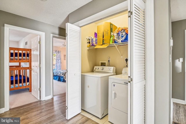 laundry room featuring a textured ceiling, light hardwood / wood-style flooring, and washer and clothes dryer