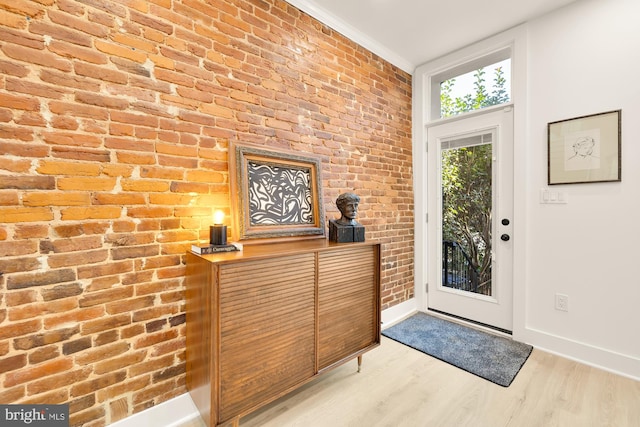 foyer entrance with brick wall and light hardwood / wood-style flooring