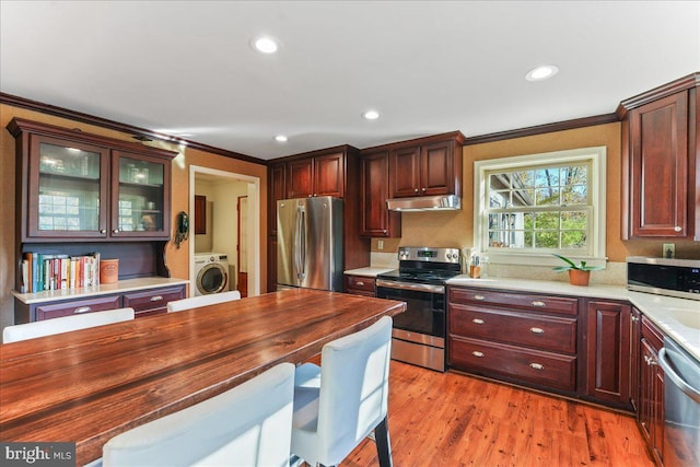 kitchen featuring washer / dryer, crown molding, appliances with stainless steel finishes, and light hardwood / wood-style flooring