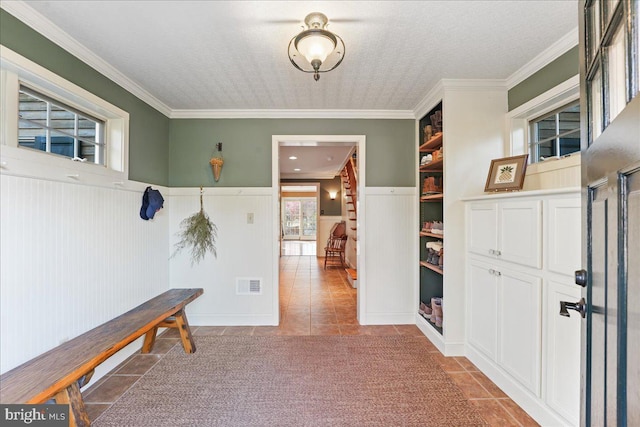 corridor with crown molding, light tile patterned flooring, and a textured ceiling