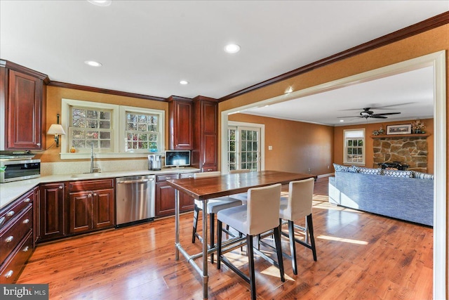 kitchen featuring light wood-type flooring, ornamental molding, a wealth of natural light, and stainless steel dishwasher