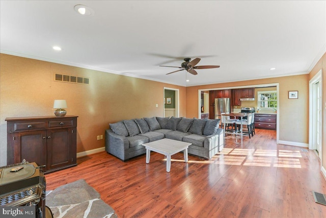 living room featuring ceiling fan, hardwood / wood-style flooring, and ornamental molding