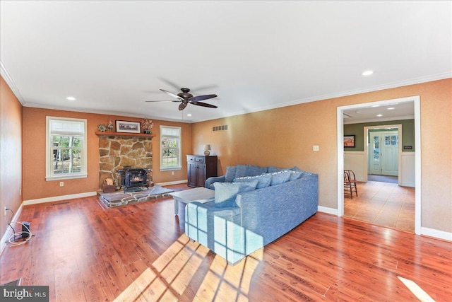 living room with crown molding, hardwood / wood-style flooring, a wood stove, and ceiling fan