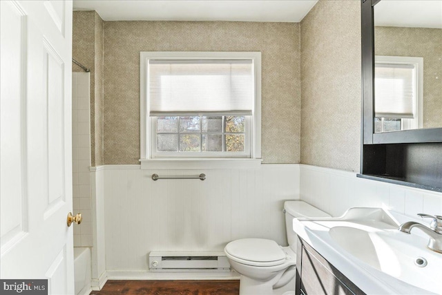 full bathroom featuring shower / washtub combination, a baseboard heating unit, wood-type flooring, toilet, and vanity