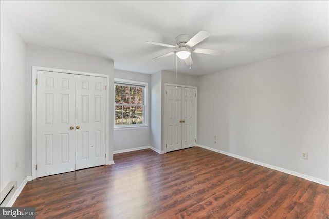 unfurnished bedroom featuring multiple closets, ceiling fan, a baseboard radiator, and dark hardwood / wood-style flooring