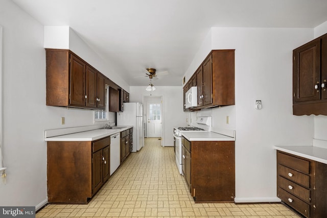 kitchen with ceiling fan, dark brown cabinetry, white appliances, and sink