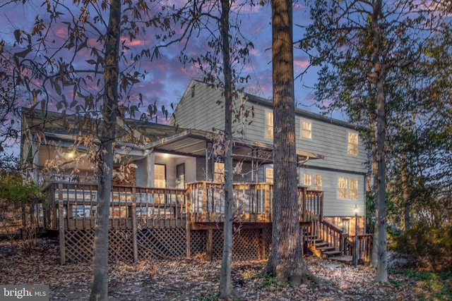 back house at dusk featuring a deck