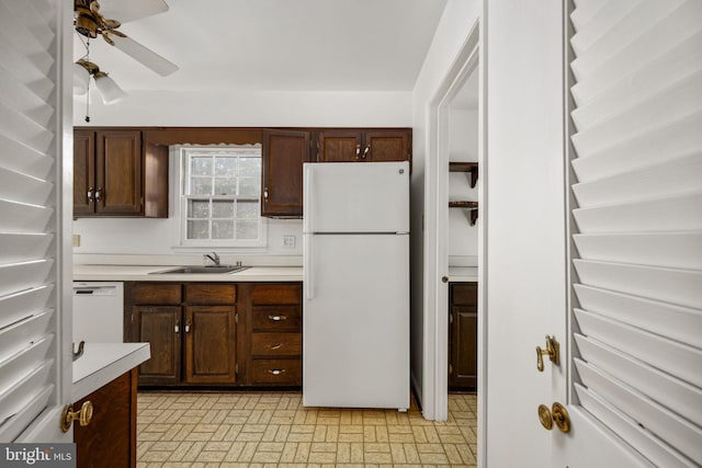 kitchen with dark brown cabinetry, white appliances, ceiling fan, and sink