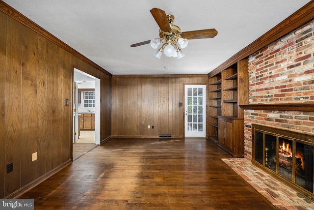 unfurnished living room with wooden walls, built in features, and a brick fireplace