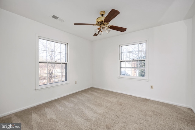 empty room with a wealth of natural light, light carpet, and ceiling fan