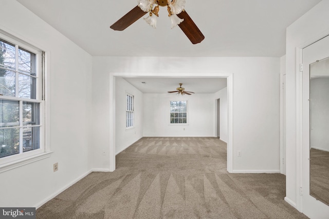 unfurnished living room with a wealth of natural light, ceiling fan, and light colored carpet