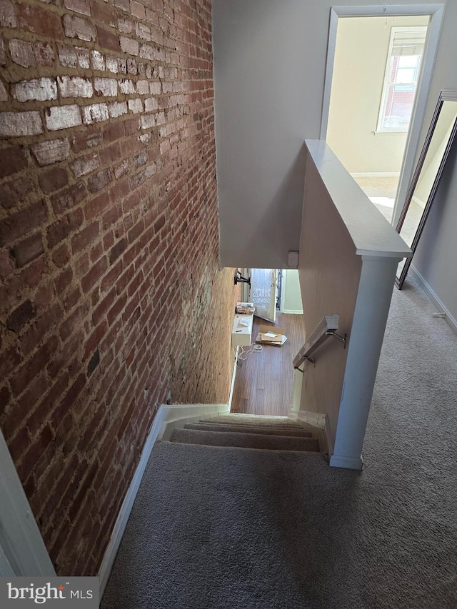 staircase with carpet and brick wall